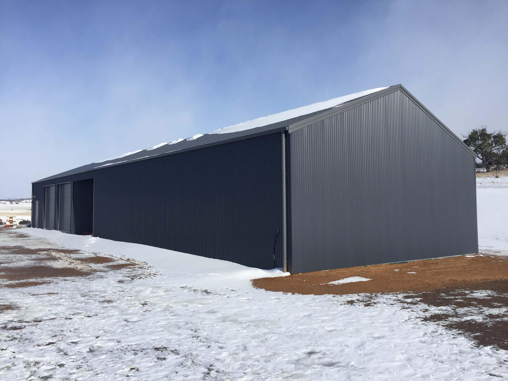 Industrial grey shed in the snow - Snowy Sheds