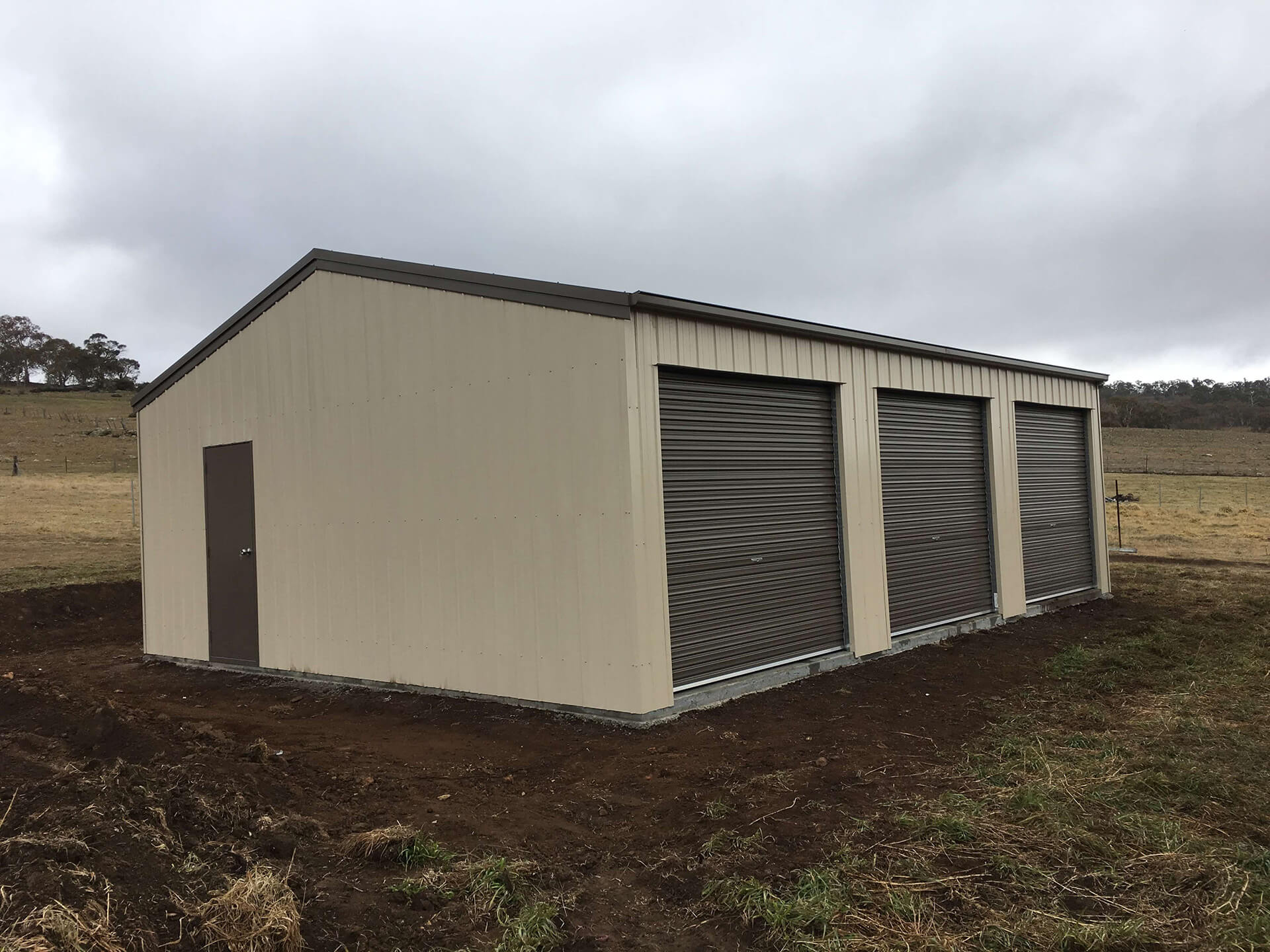 cream shed with 3 black doors side view  - Snowy Sheds