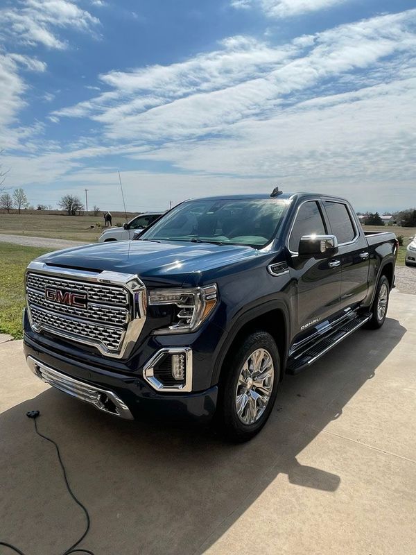 A blue gmc sierra pickup truck is parked in a driveway.