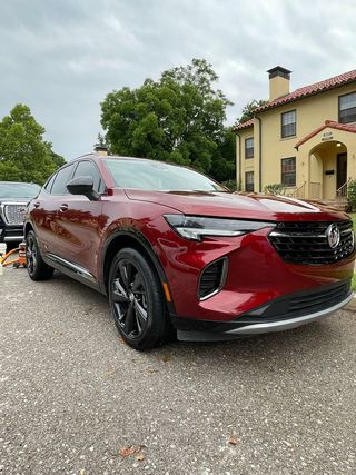 A red car is parked in a driveway in front of a house.