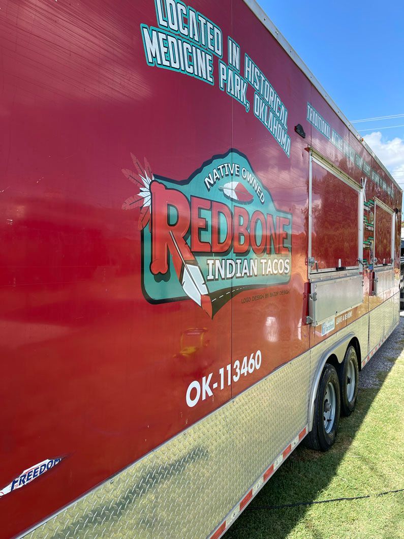 A red trailer is parked in a grassy field.