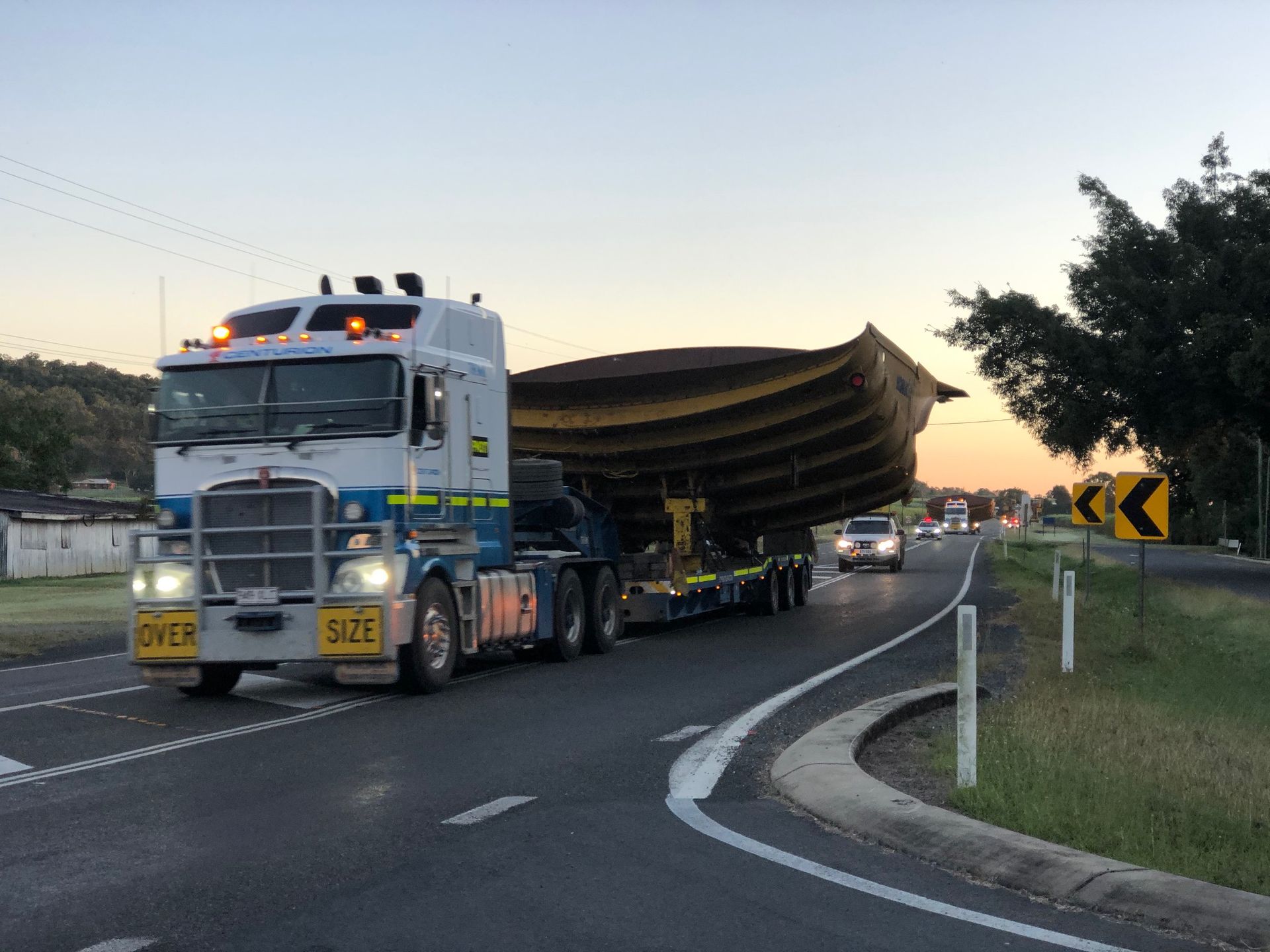 A Large, Yellow, Oversized Load Being Transported on a Highway, Escorted by Two Vehicles — Col Adamson Transport Services in Farleigh, QLD