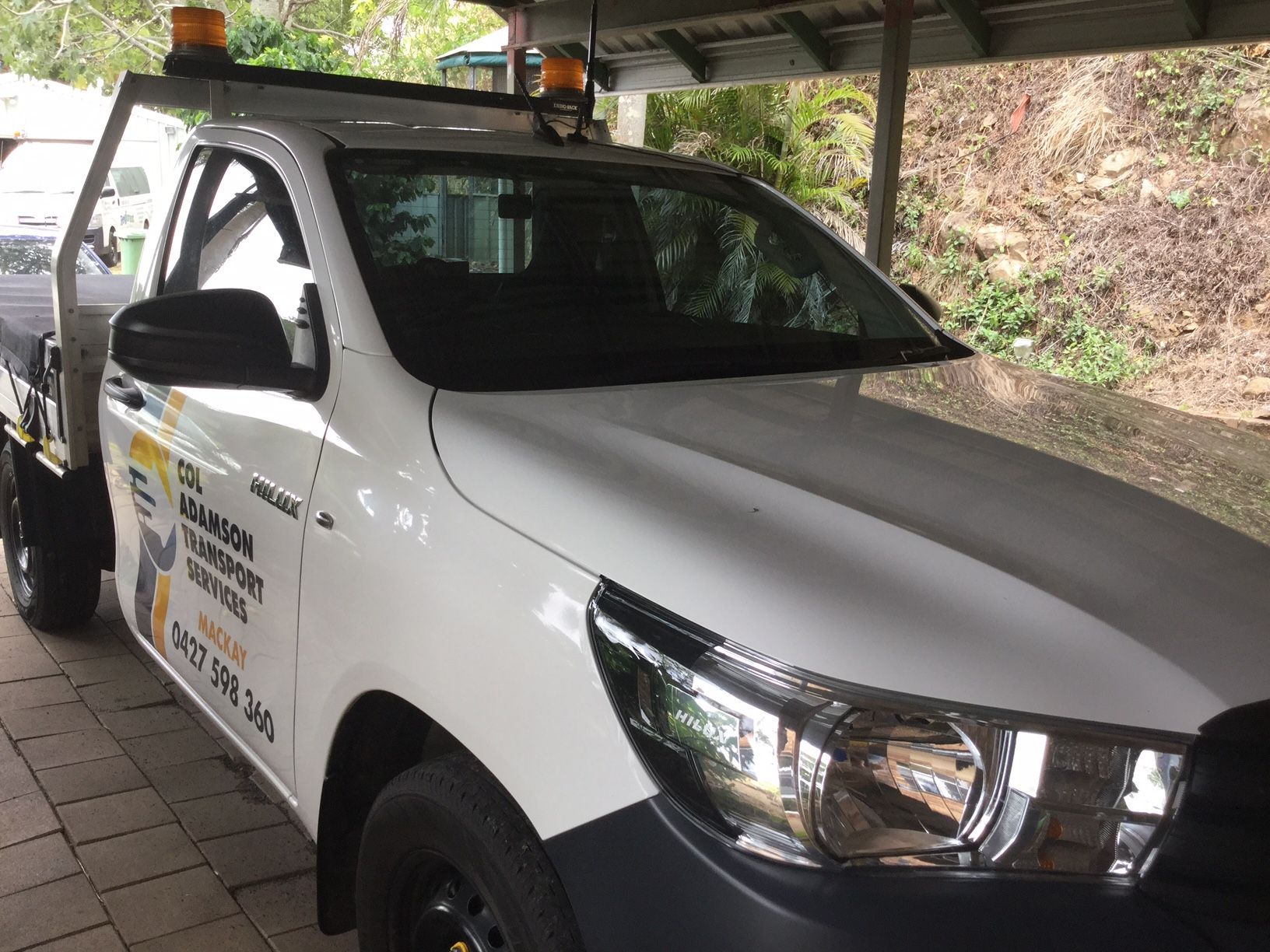 White Toyota Hilux Utility Truck With Company Signage Under a Covered Area — Col Adamson Transport Services in Farleigh, QLD