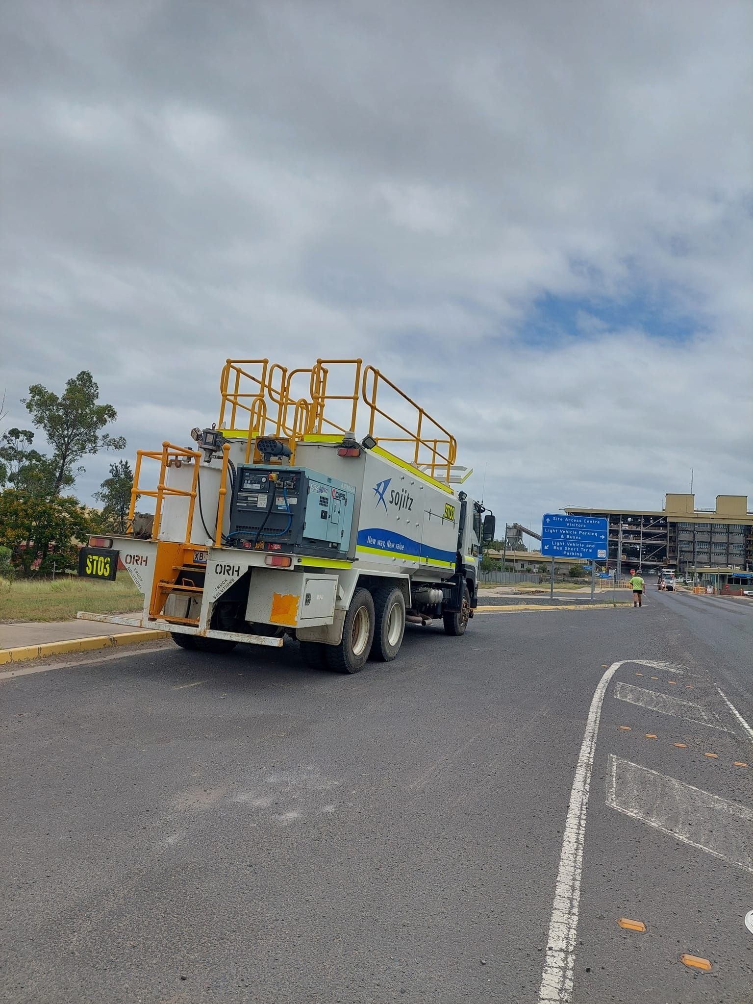 A utility truck with a yellow elevated platform parked on an asphalt road under a cloudy sky — Col Adamson Transport Services in Farleigh, QLD