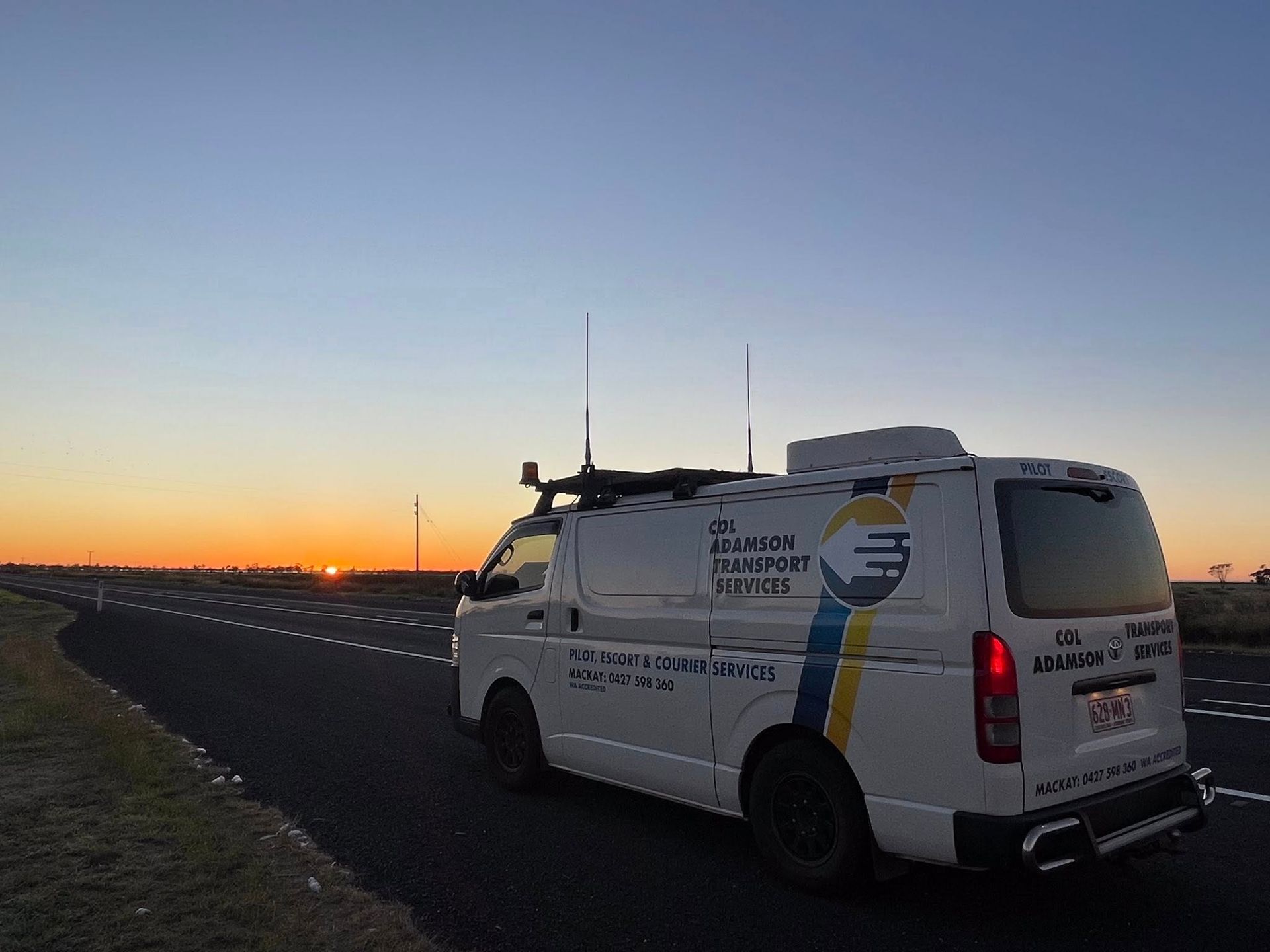 A white service van with communications equipment parked on the side of a road during a sunset — Col Adamson Transport Services in Farleigh, QLD