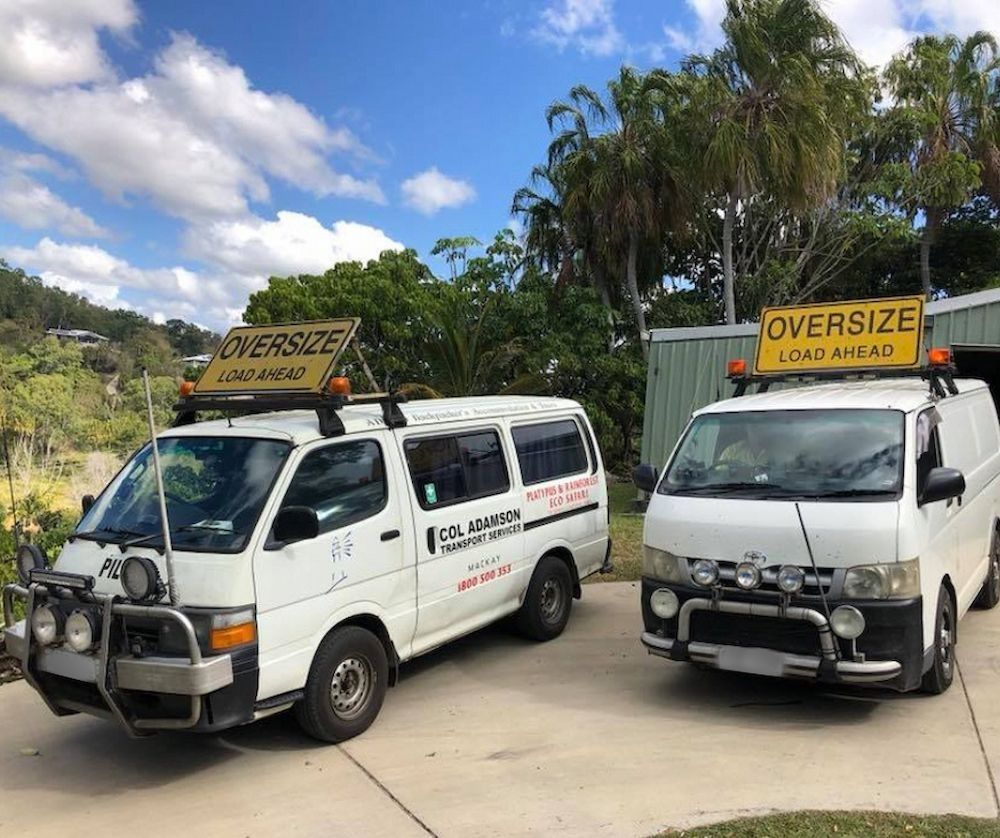 Two White Vans With Signs Parked Outdoors — Col Adamson Transport Services in Moranbah, QLD