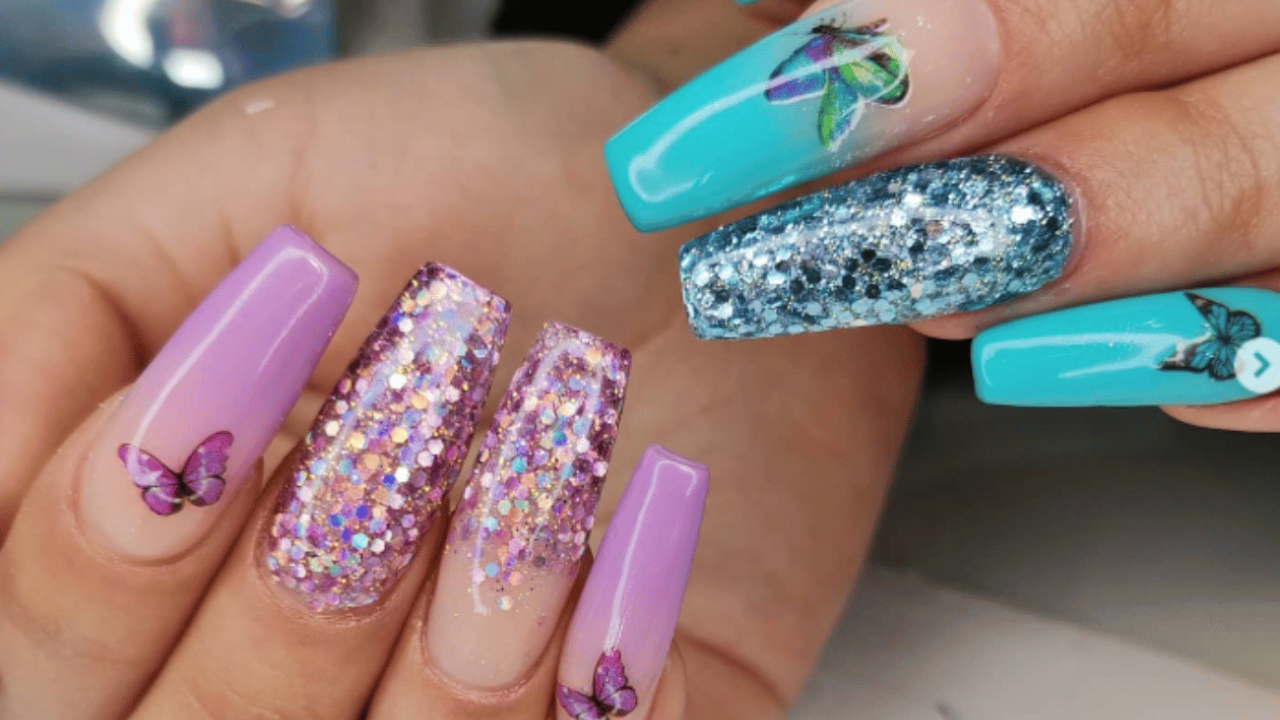 Un primer plano de las uñas de una persona con un diseño de mariposa en ellas.