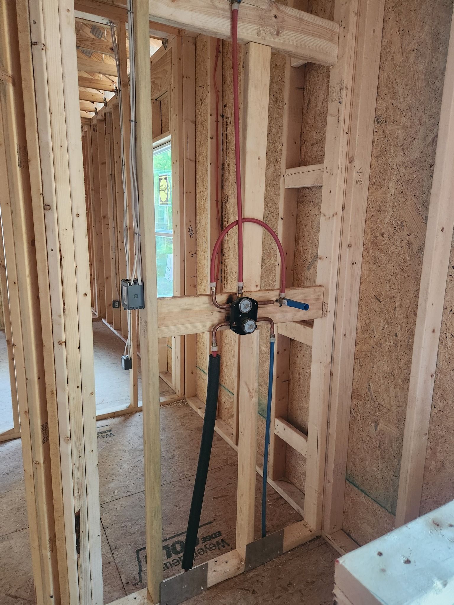 Framed wooden bathroom walls with plumbing fixtures installed.