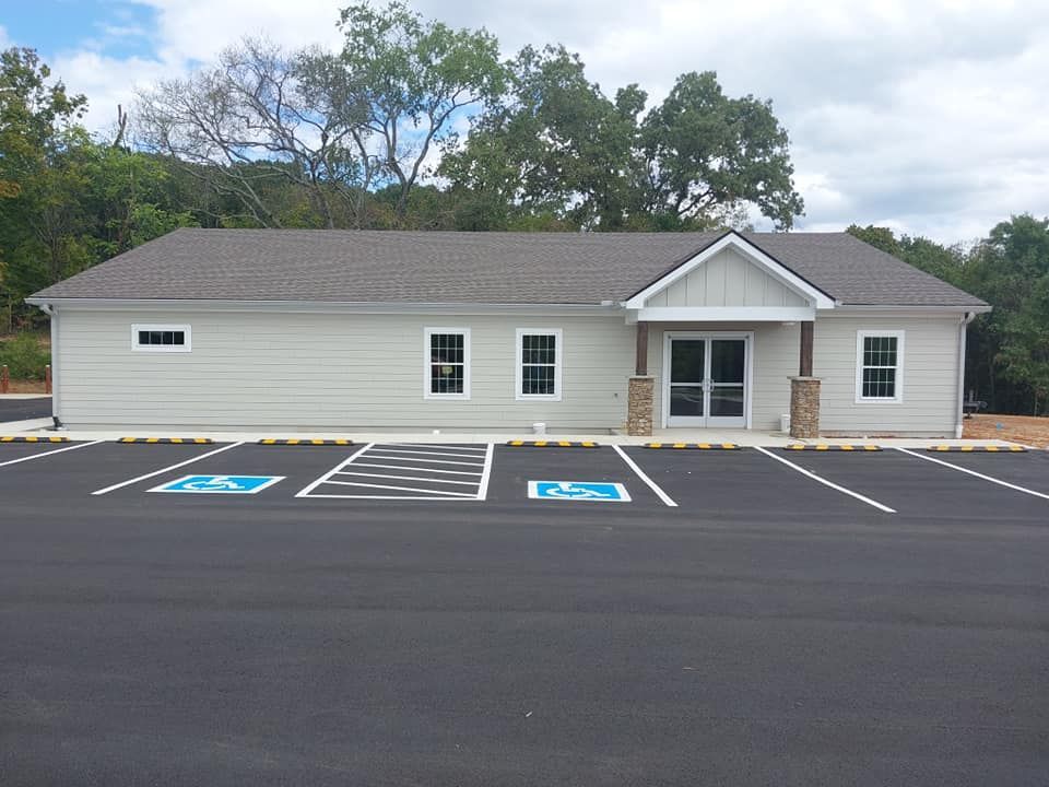 A light gray building with a paved parking lot and handicap parking spaces.