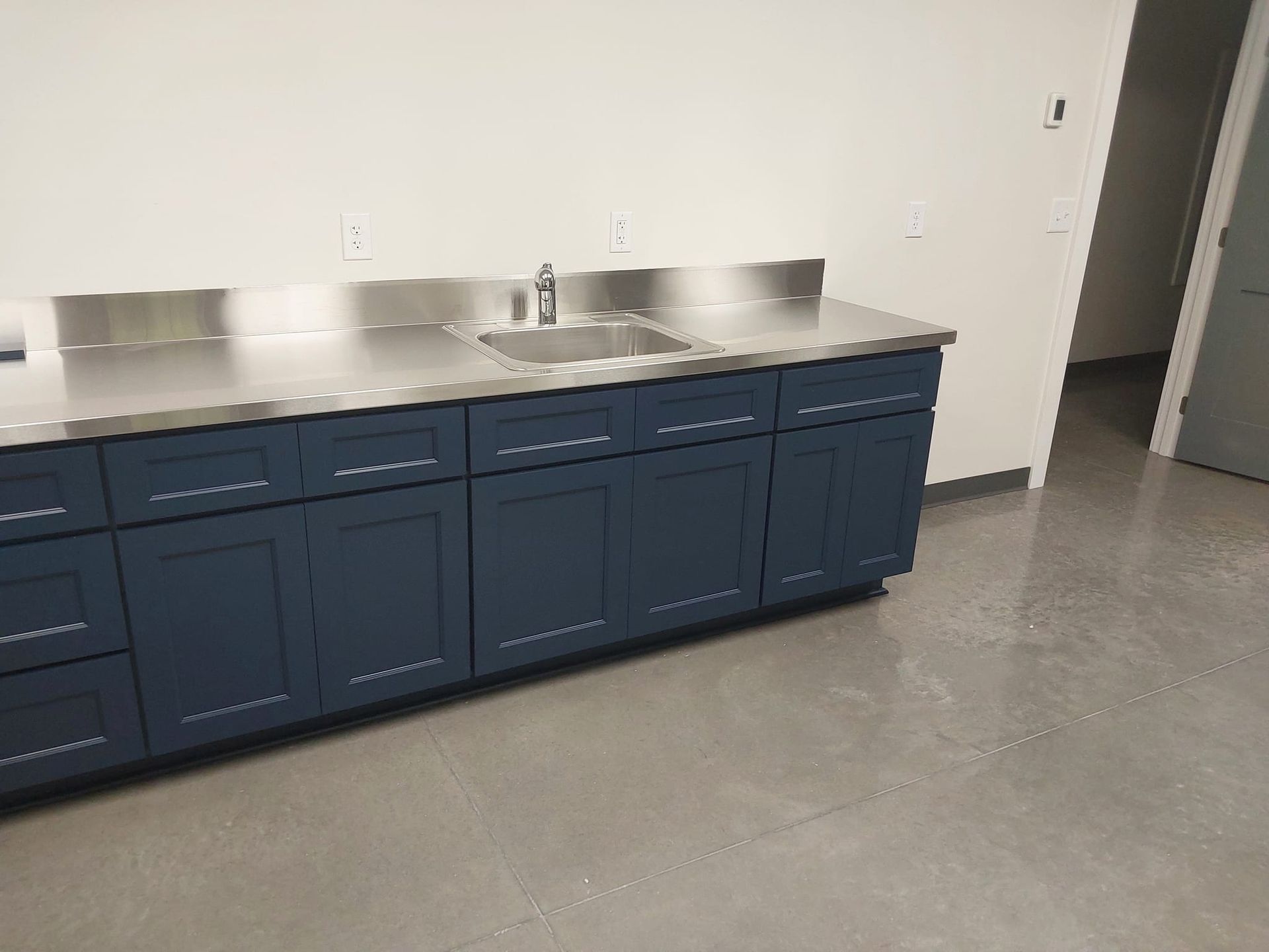 Blue cabinets with stainless steel countertop and sink.