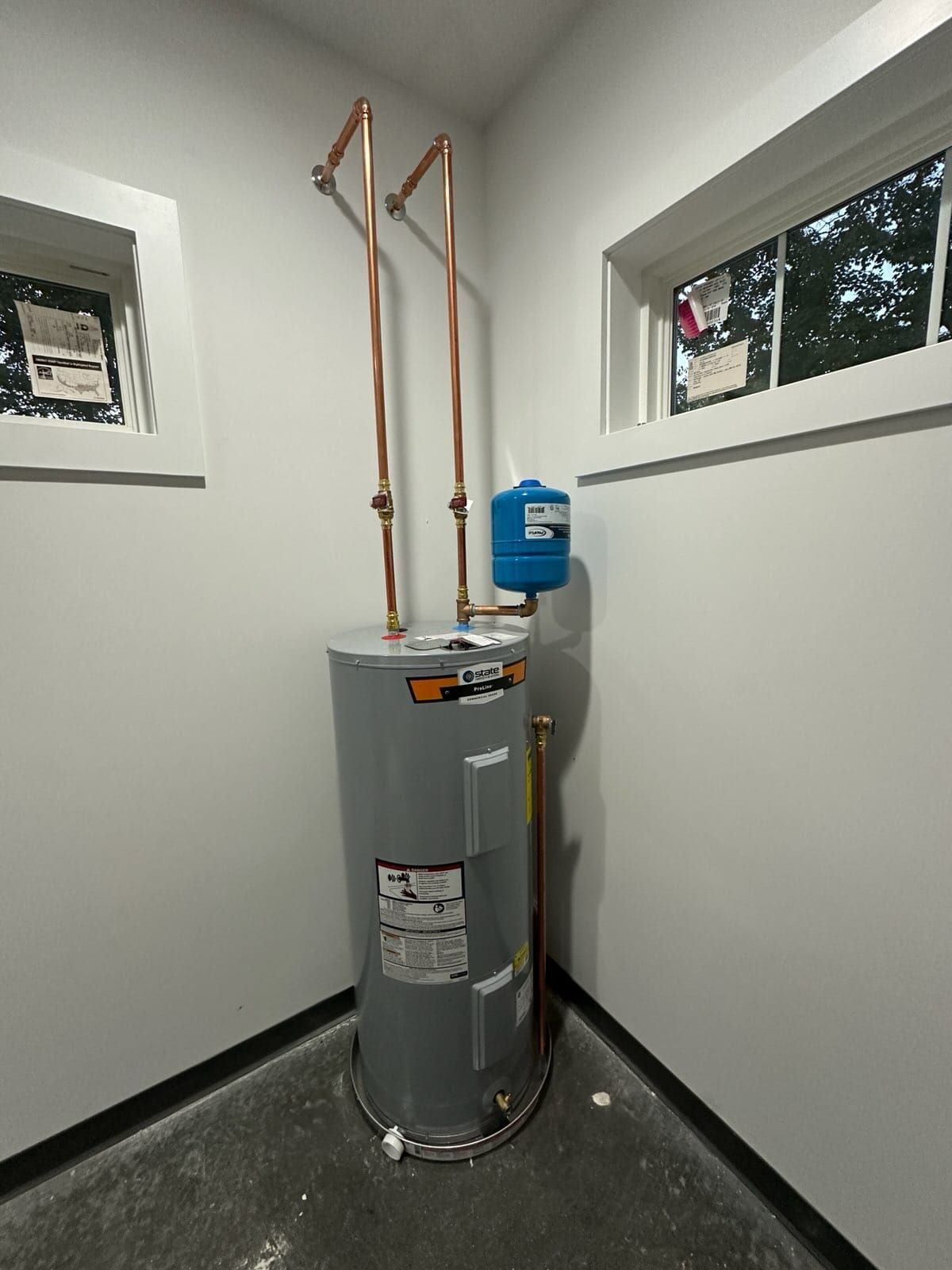 A new water heater in a corner, with copper pipes and an expansion tank.
