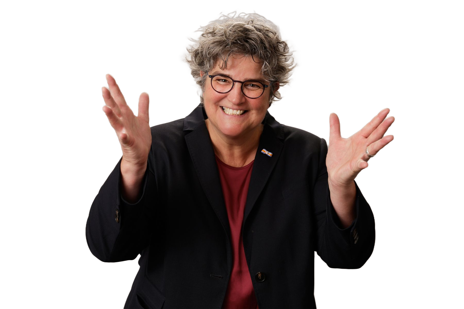 Vrouw met bril lacht, met uitgestrekte armen, gekleed in een blazer.