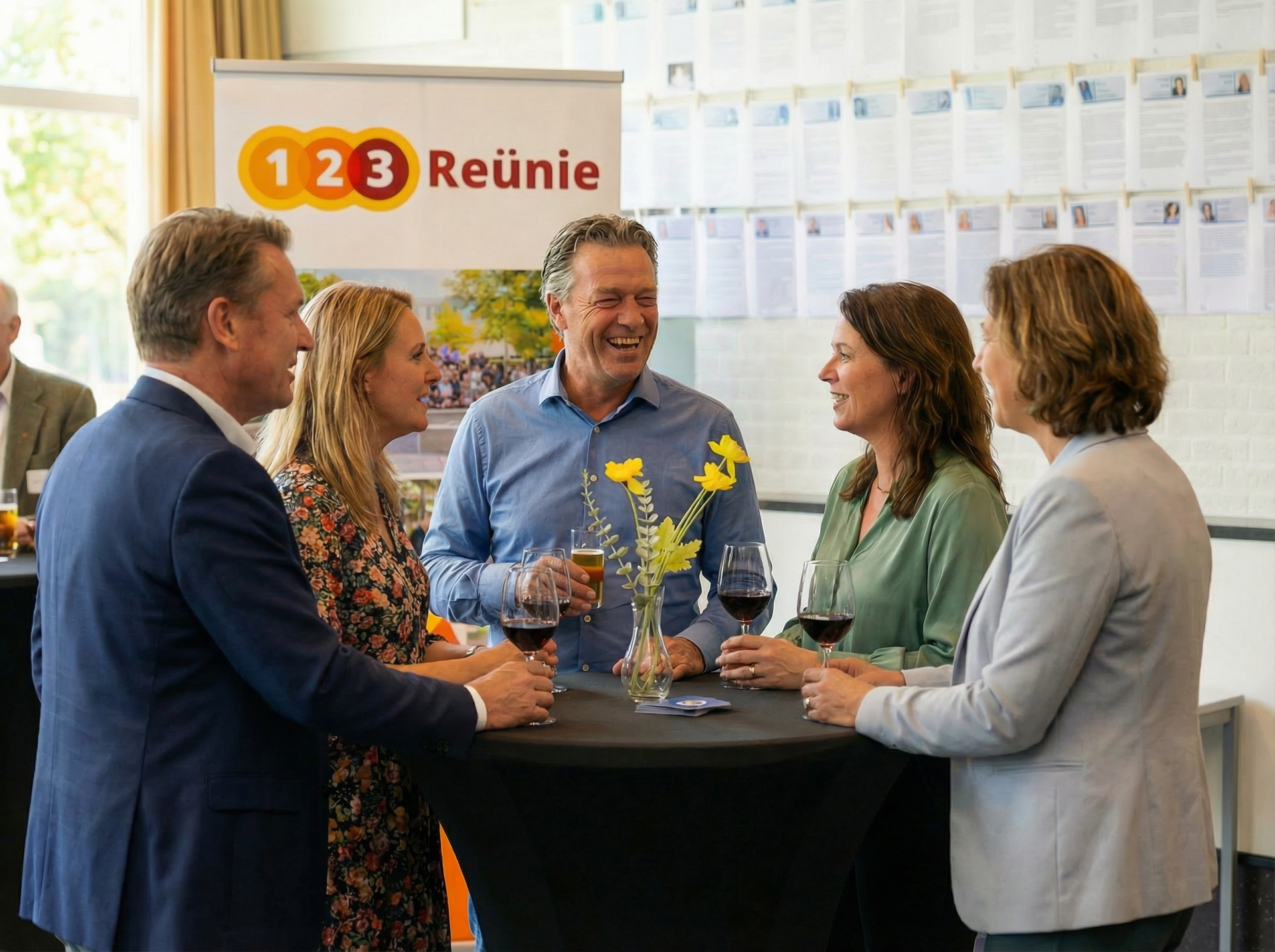 Mensen praten met elkaar rond een kleine tafel, terwijl ze een drankje vasthouden. 