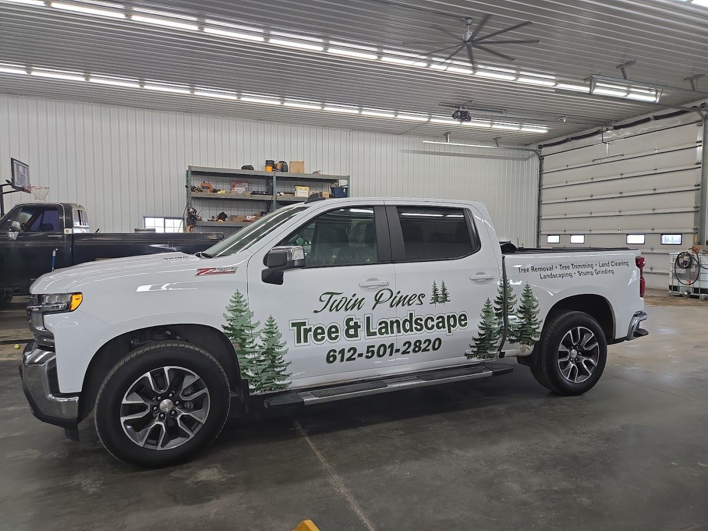 White Twin Pines Tree & Landscape pickup truck parked inside a large, industrial garage.