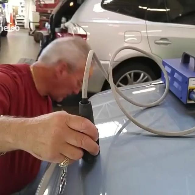 Mechanic using a hand pump to check a car tire in a garage