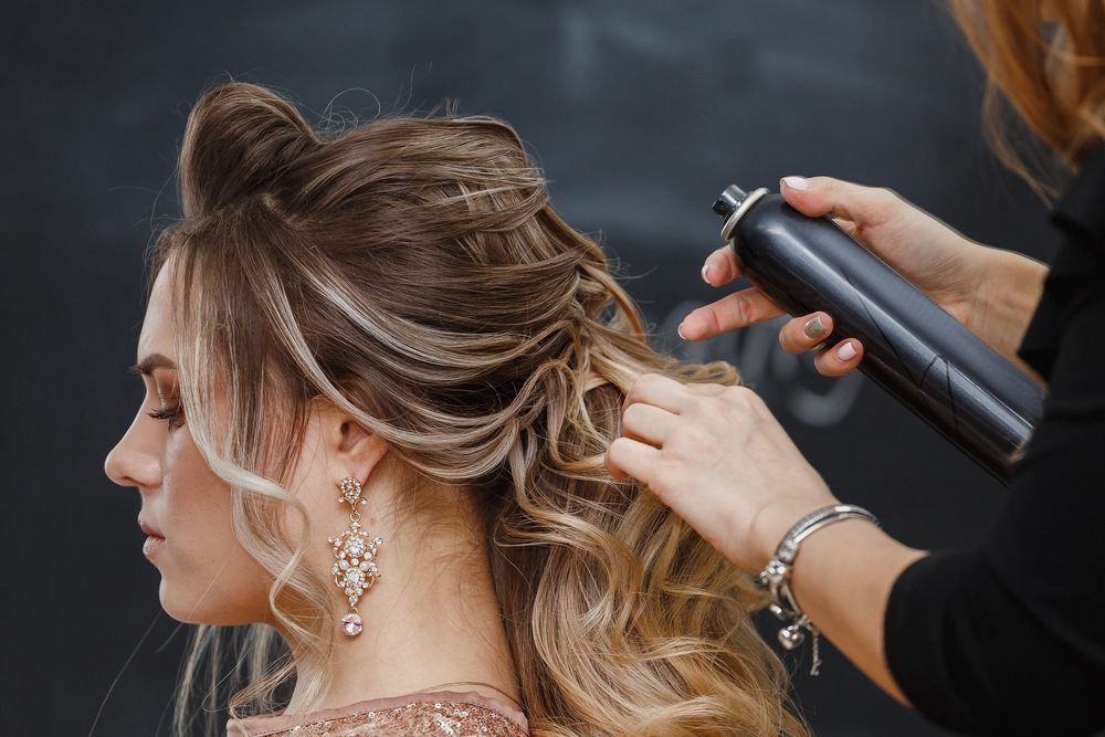 Applying Hairspray On Woman's Styled Hair — Hair Salon in Sippy Downs, QLD