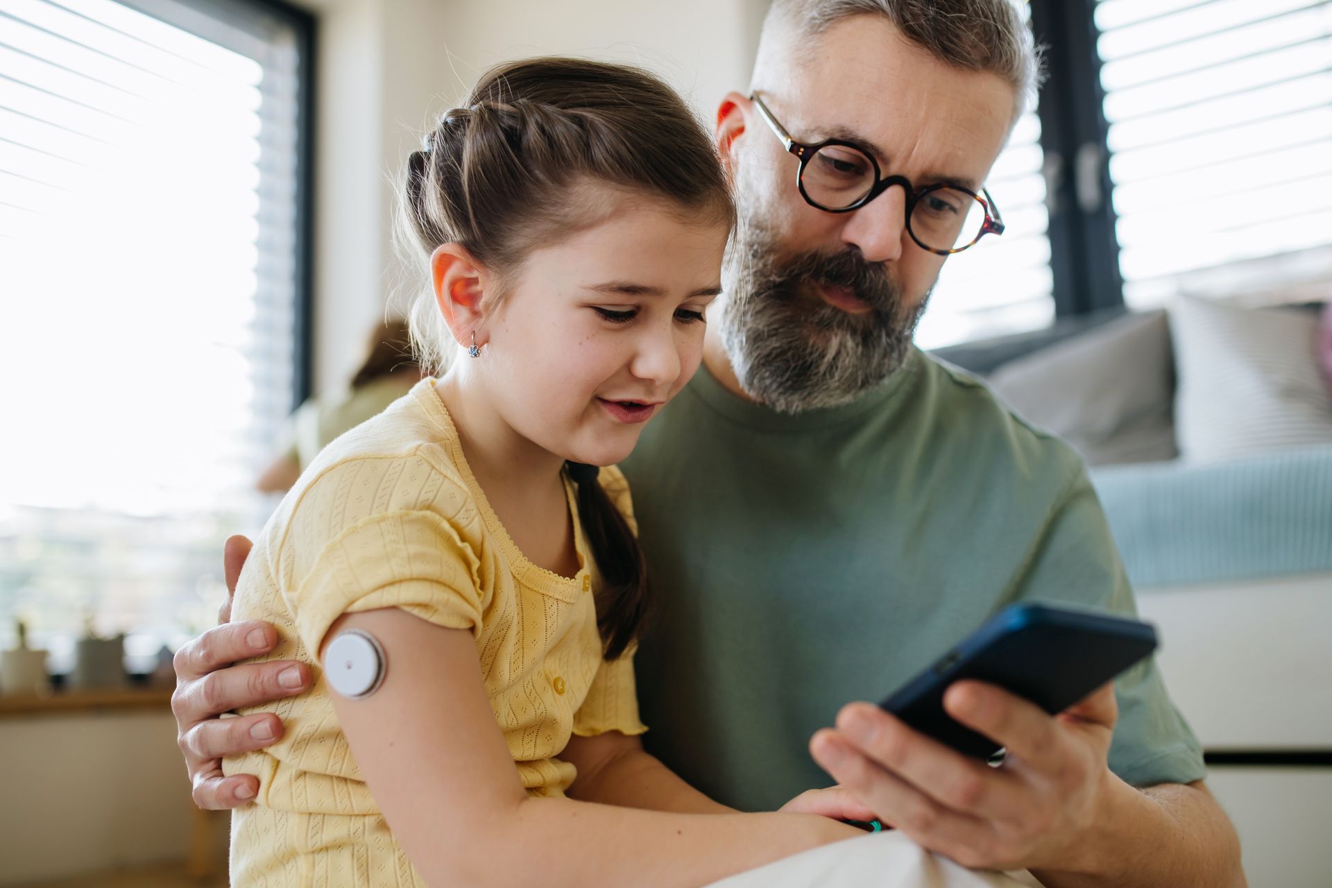 Man and child looking at a phone, child has sensor on arm.