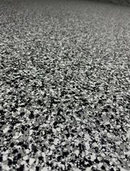 Close-up of a monochromatic garage floor coating with a speckled black, white, and gray vinyl chip texture.