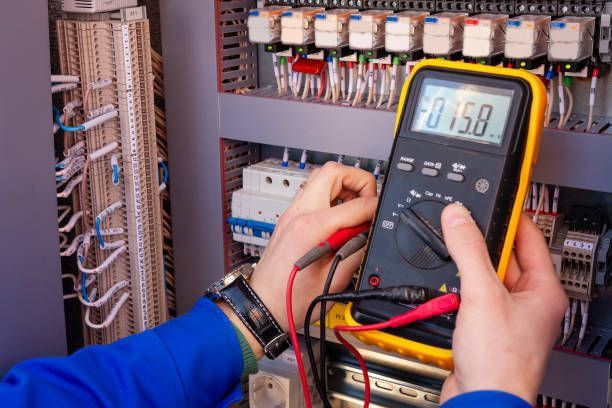 Electrician with multimeter in hands testing electrical circuit for John E. McLeod Electrical in Fal