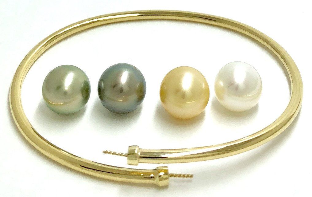 A gold choker necklace with two exposed threaded posts alongside four loose, round pearls in green, grey, gold, and white.