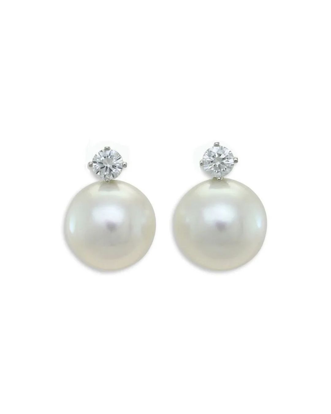 A pair of stud earrings, each featuring a white round pearl topped by a small, brilliant-cut diamond in a silver setting.