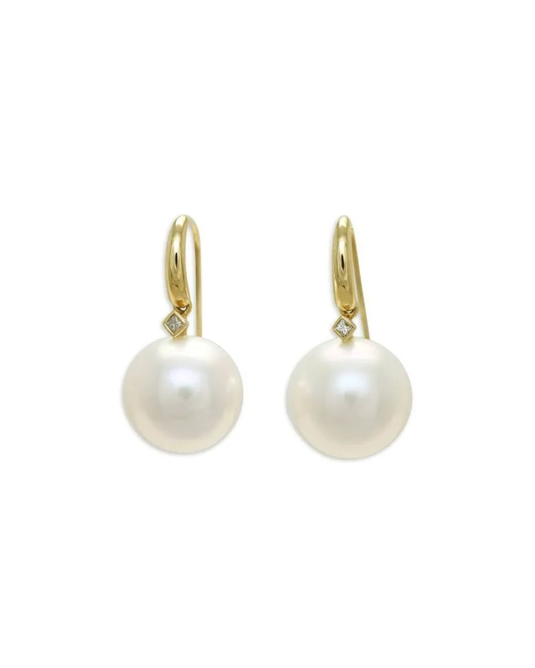 A pair of gold hook earrings, each featuring a small square-cut diamond atop a large, round white pearl.