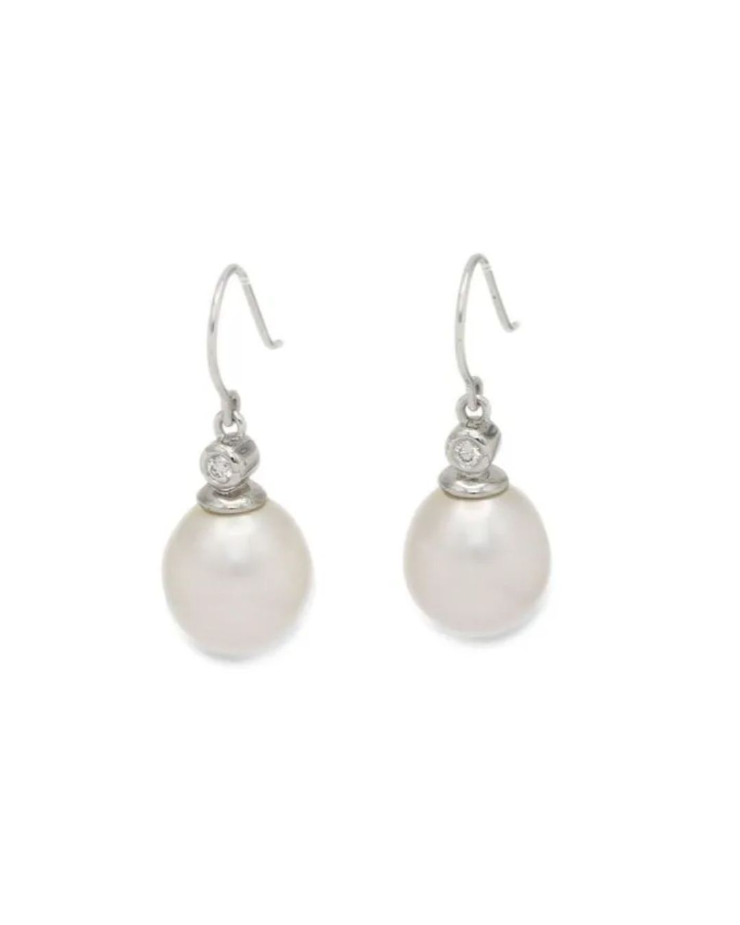 A pair of white pearl drop earrings with small diamonds set in silver, hanging from fishhook backs on a white background.