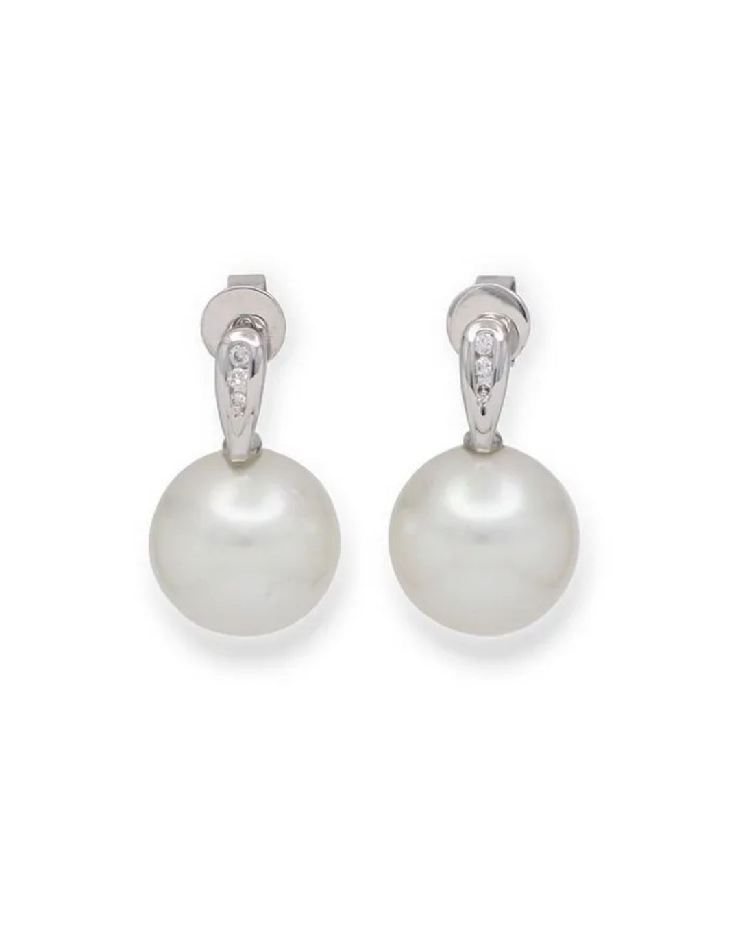 A pair of white pearl drop earrings with small diamond accents on silver settings against a white background.