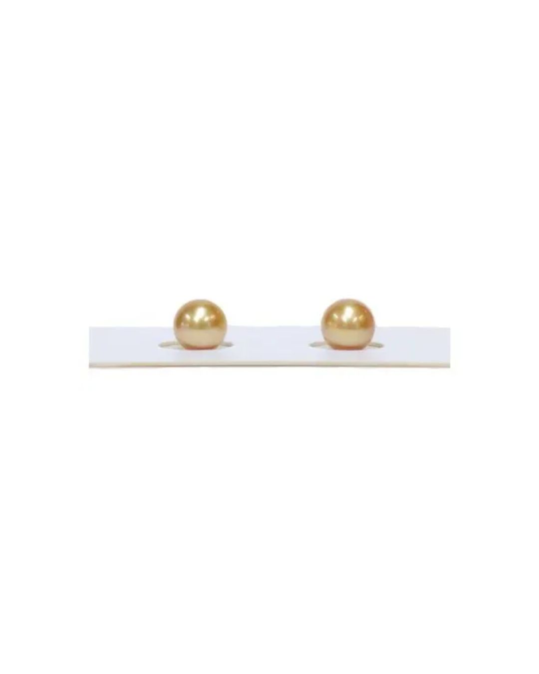 Two round, lustrous golden pearls sit side-by-side on a white display card.