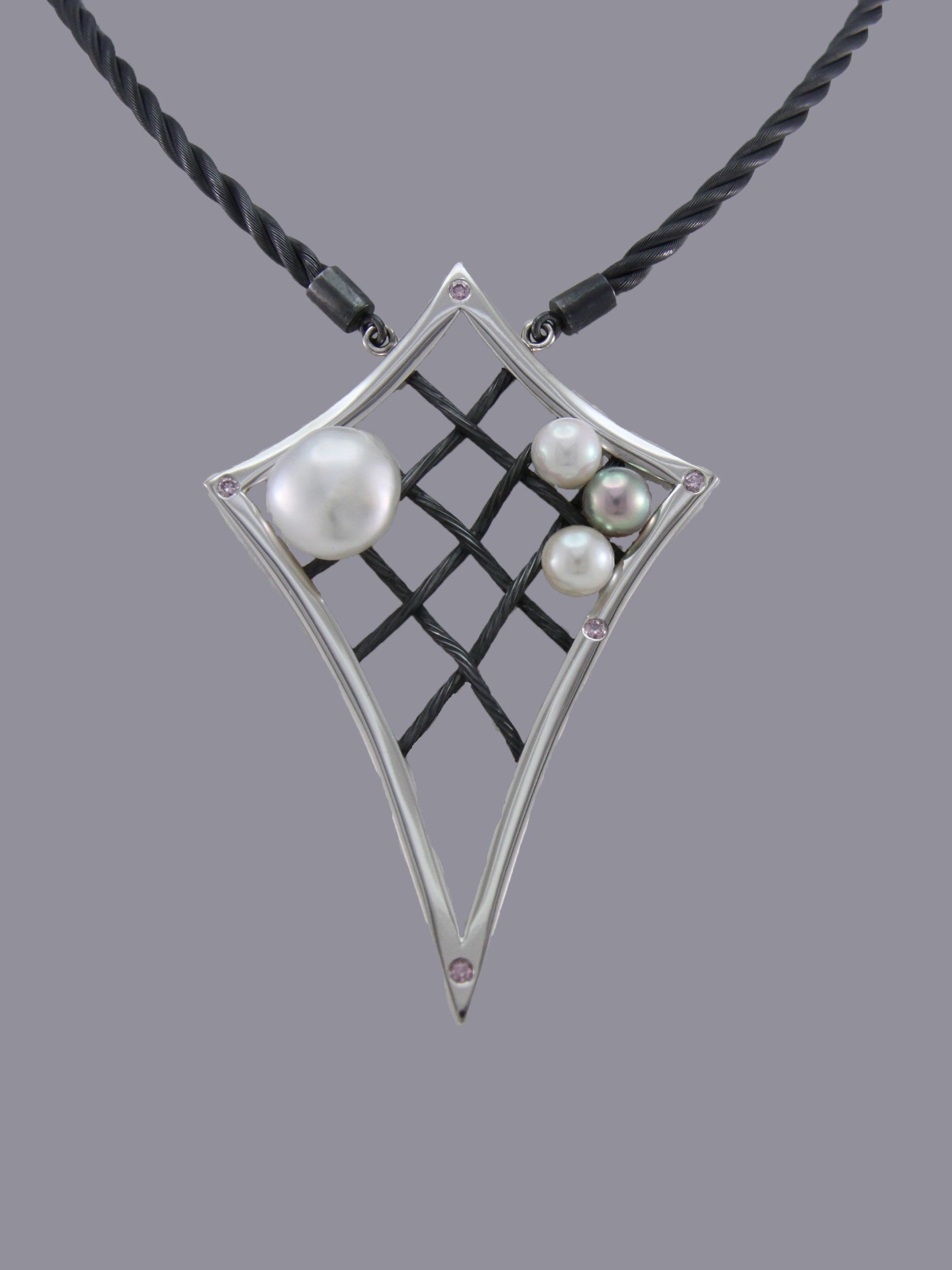 A silver, kite-shaped pendant on a black cord features a dark grid inlay accented with one large and three small pearls.