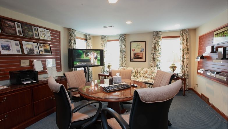 A conference room with a table and chairs and a flat screen tv