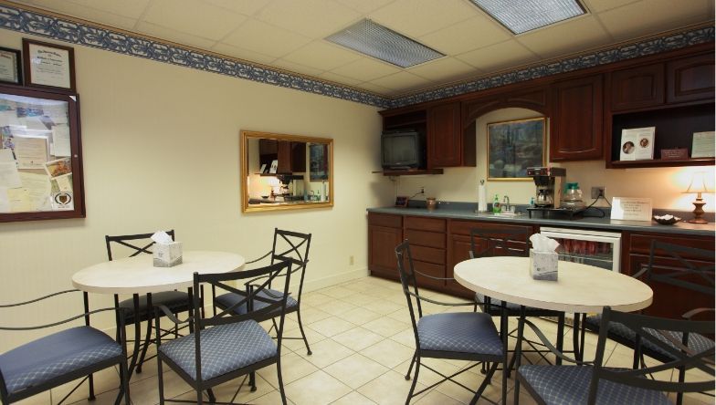 A kitchen with tables and chairs and a bulletin board