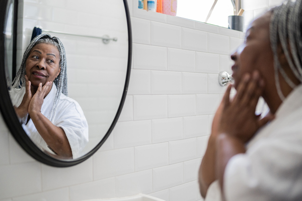 a woman is looking at her face in a bathroom mirror .