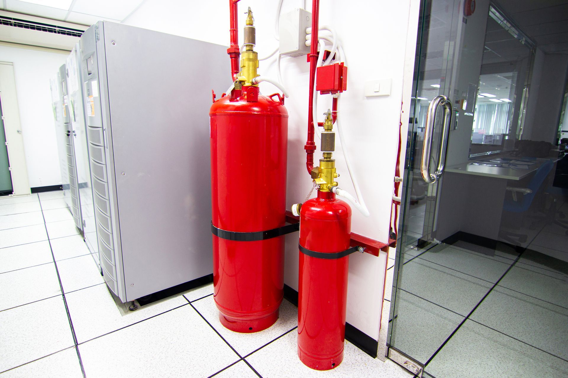 Two red fire extinguishers are sitting next to each other in a room.