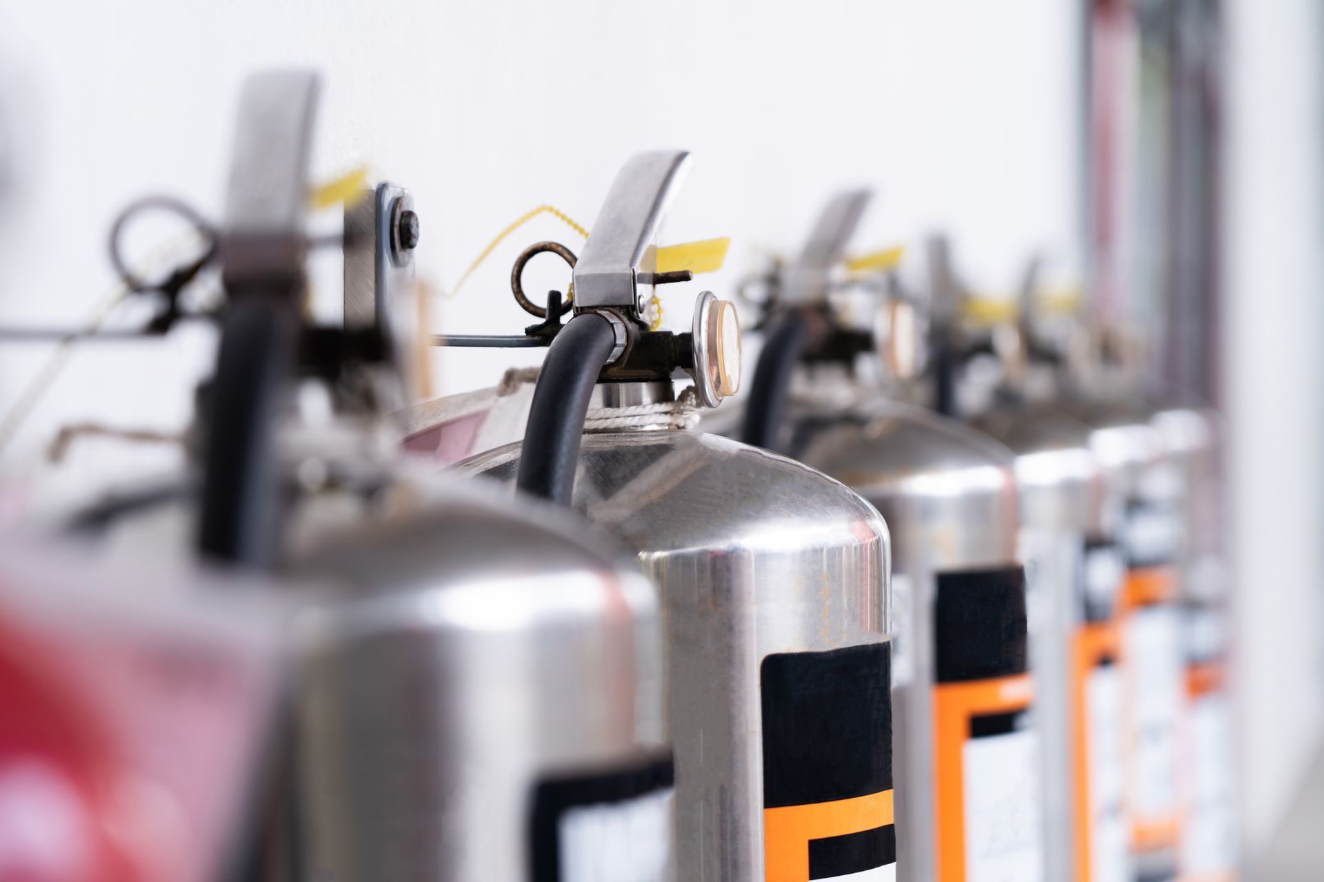 A row of fire extinguishers are lined up in a row.