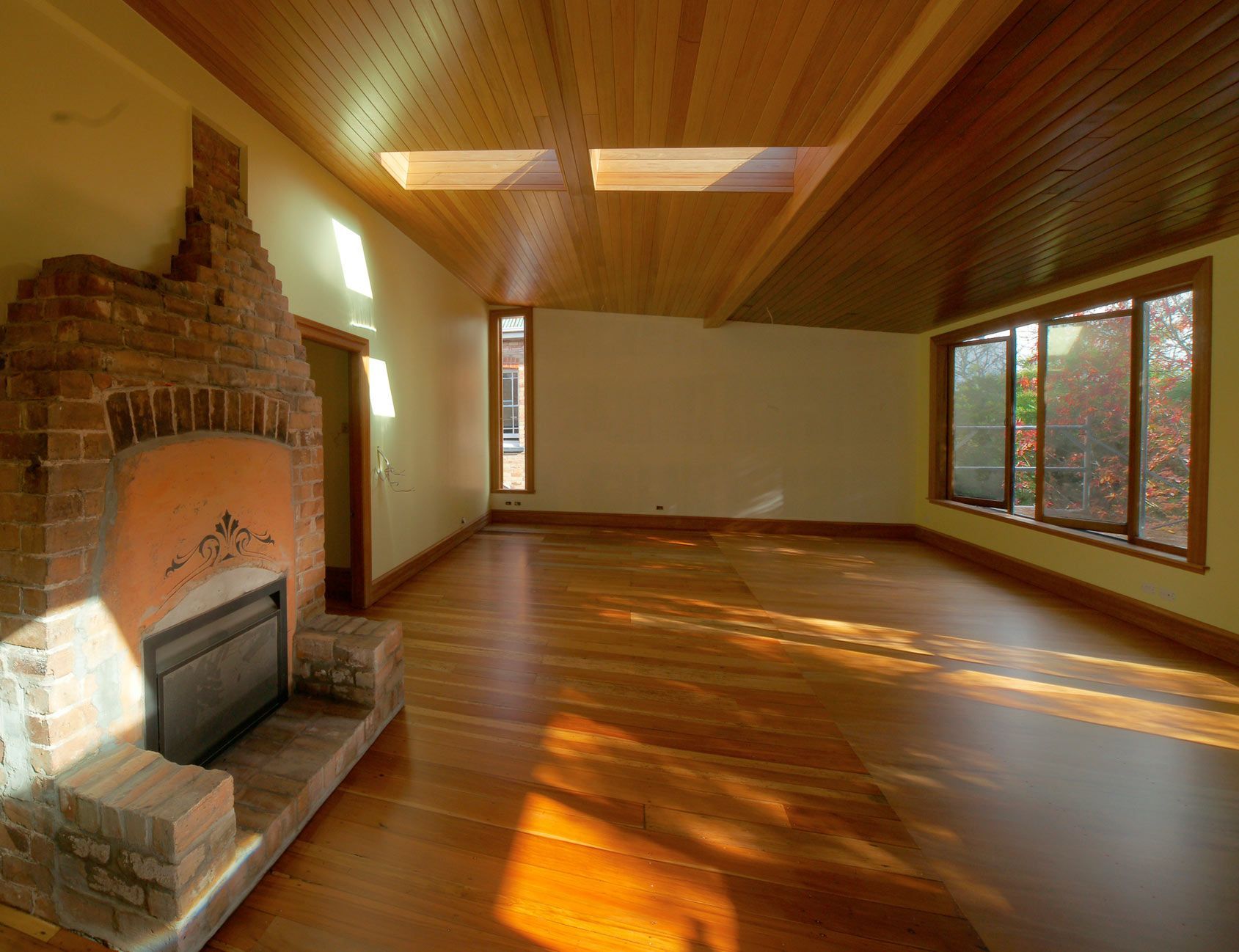 An empty living room with a fireplace and lots of windows
