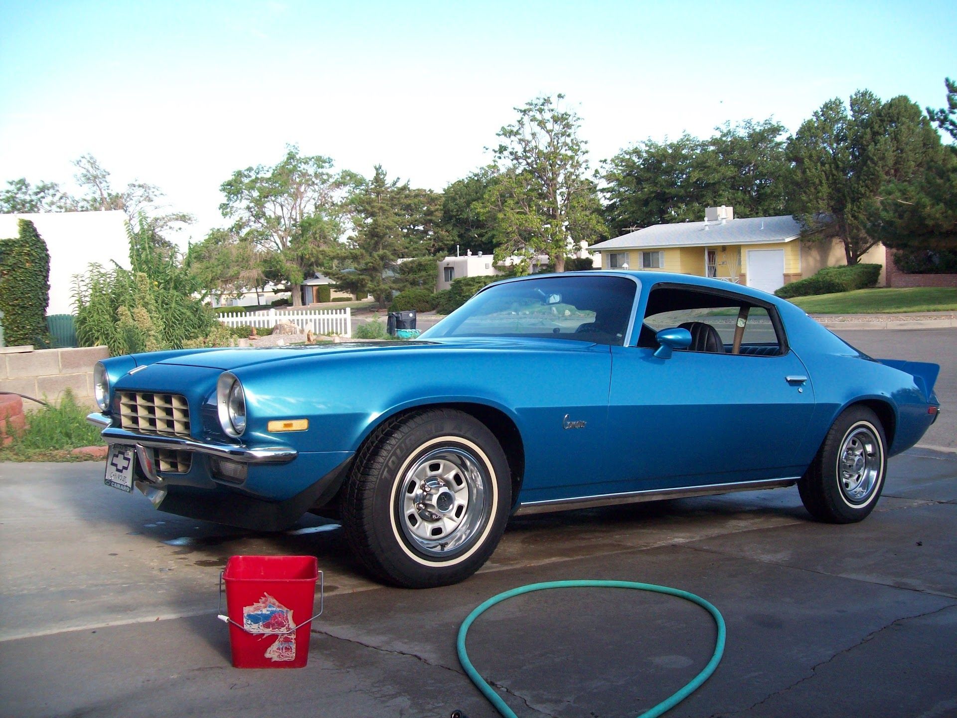 Blue 1970s Chevrolet Camaro parked in a driveway; a red bucket and a green hose are in the foreground | Chet's Wheel Alignment