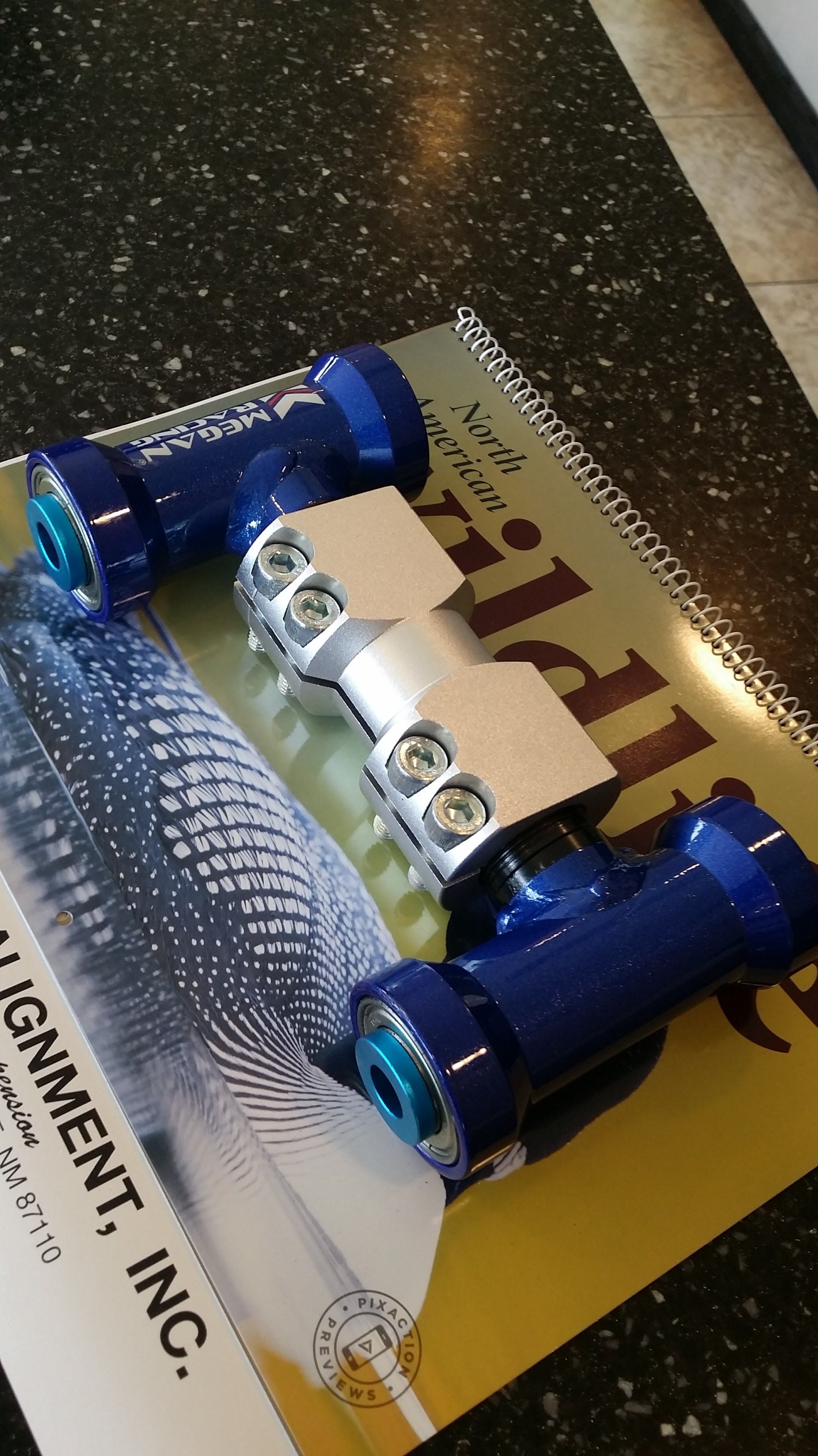 Blue and silver automotive fitting resting on a magazine | Chet's Wheel Alignment