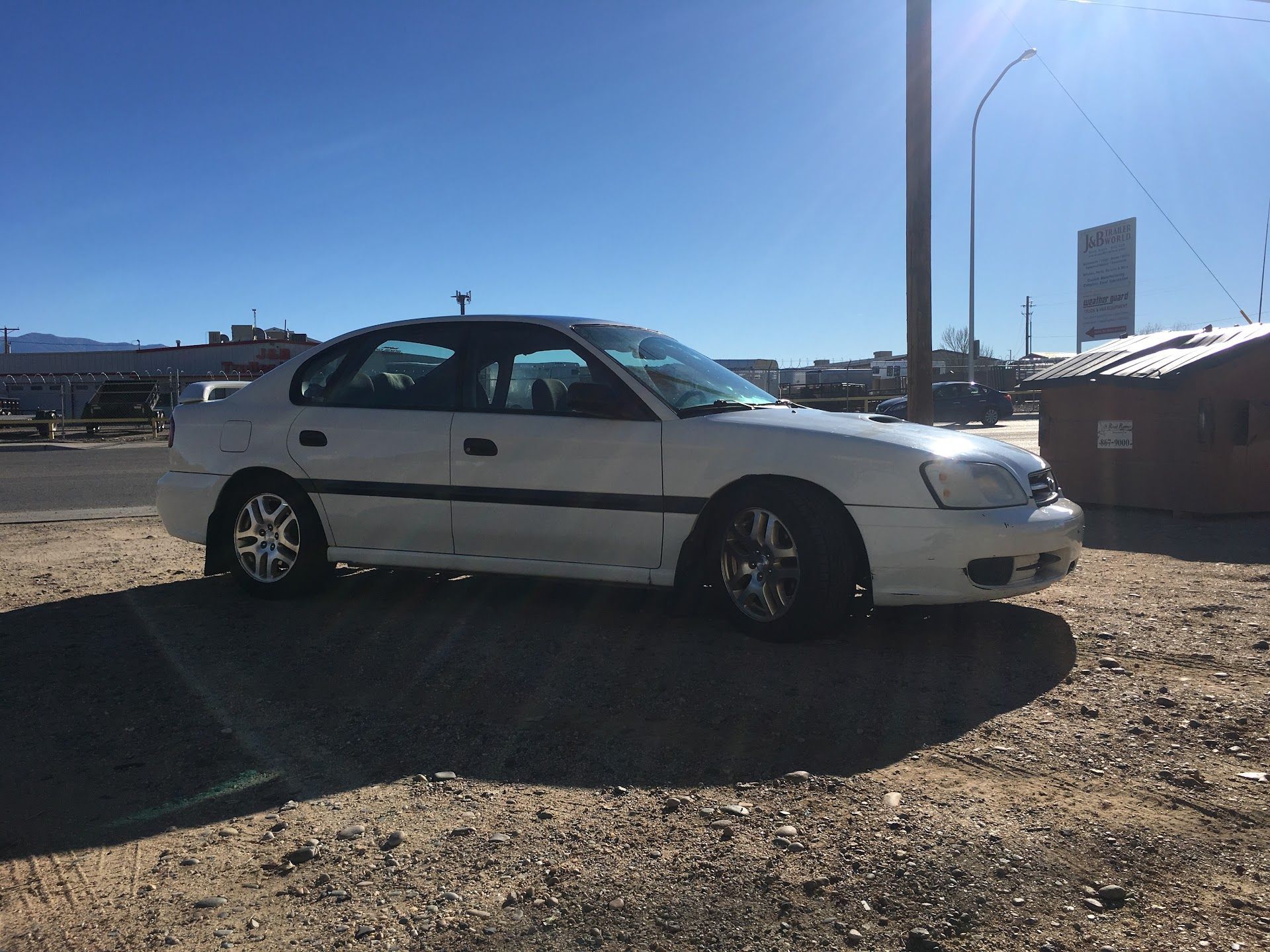White Subaru sedan parked on a dirt lot on a sunny day | Chet's Wheel Alignment