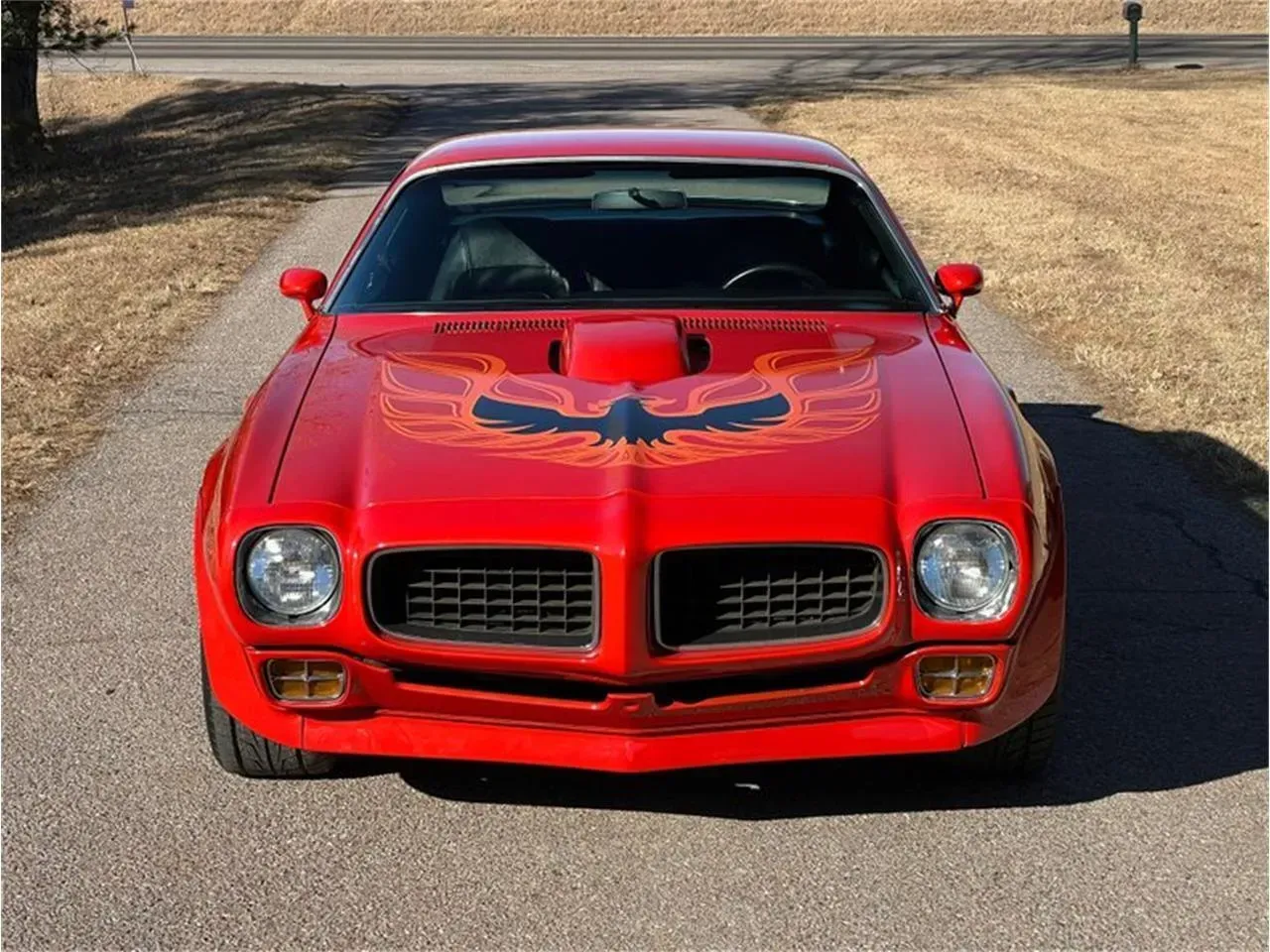 Red Pontiac Firebird Trans Am, hood with a black and orange eagle, parked on a driveway | Chet's Wheel Alignment