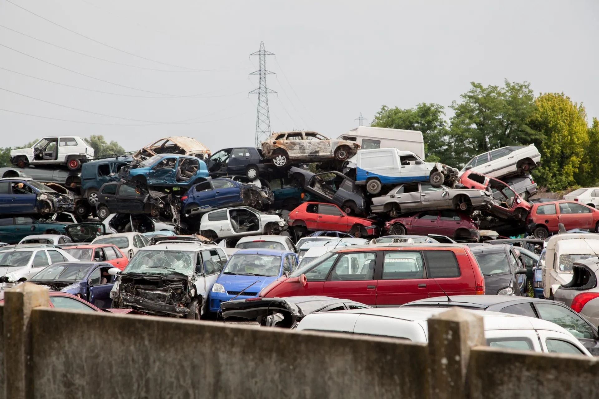 Pile of crushed and damaged cars at a junkyard, stacked on top of each other.