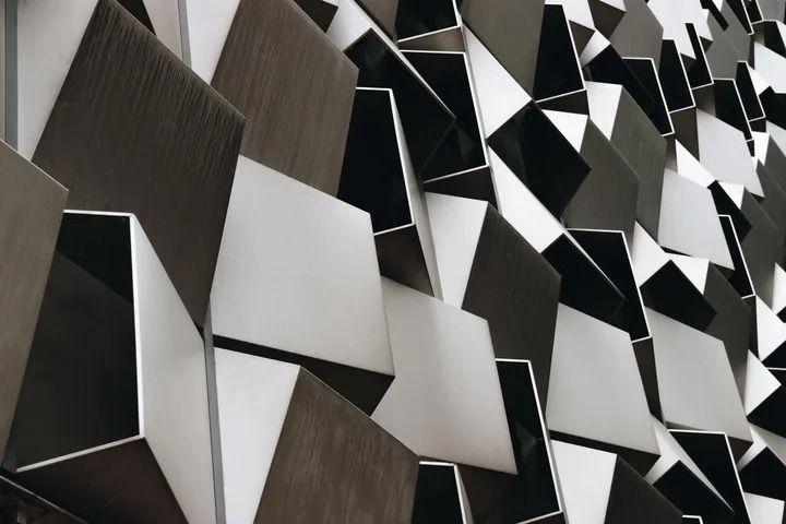 Abstract architectural facade with angular, geometric shapes in shades of gray and white.