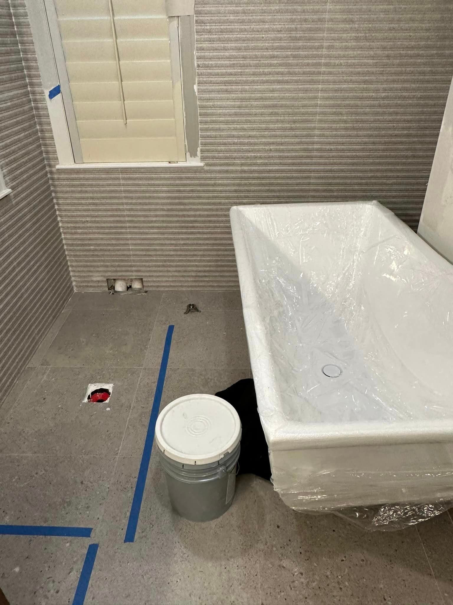 A bathroom with a bathtub and a bucket on the floor.