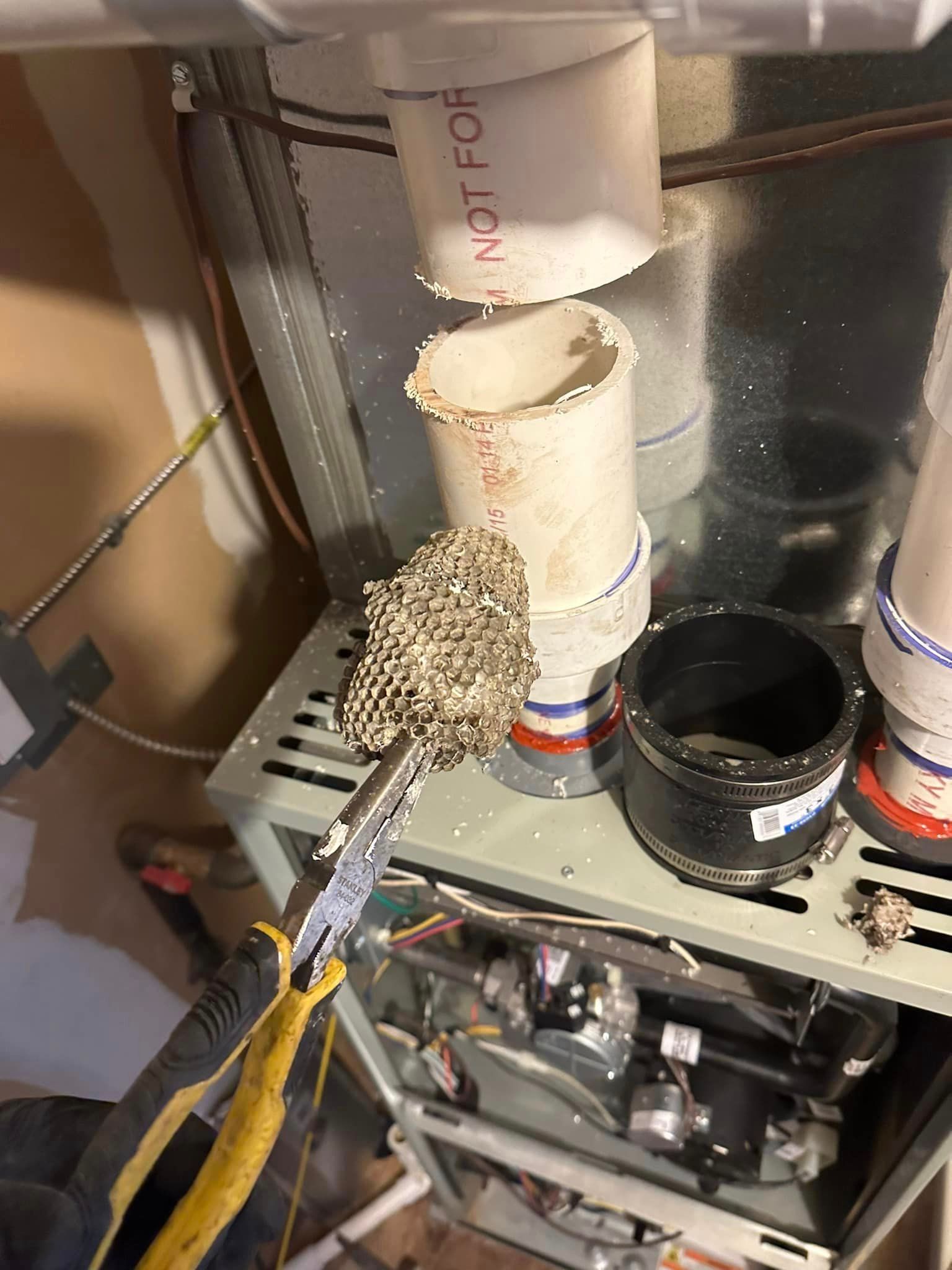 A person is working on an air conditioner with a pair of pliers.