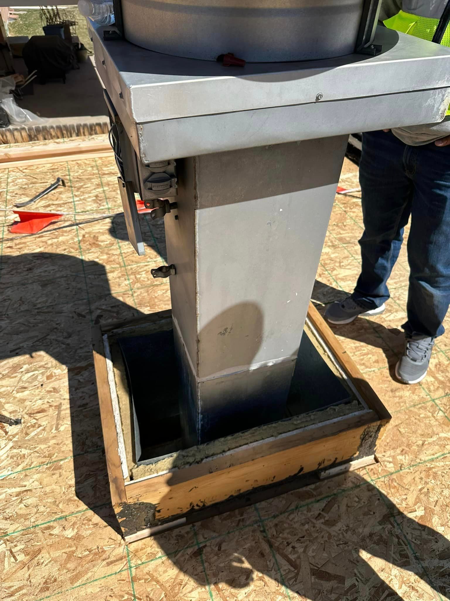 A man is standing next to a chimney on a roof.
