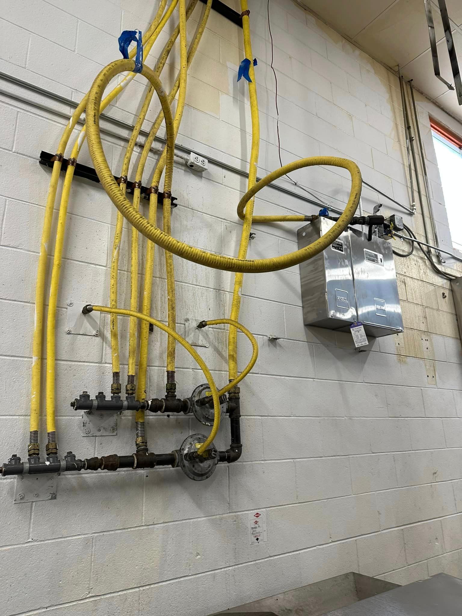 A bunch of yellow pipes are hanging on a white wall.