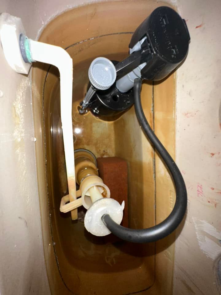 A close up of a toilet tank with a hose attached to it