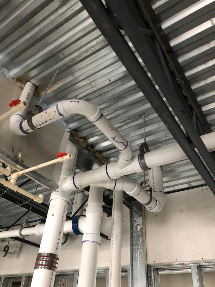 A bunch of pipes are hanging from the ceiling of a building.