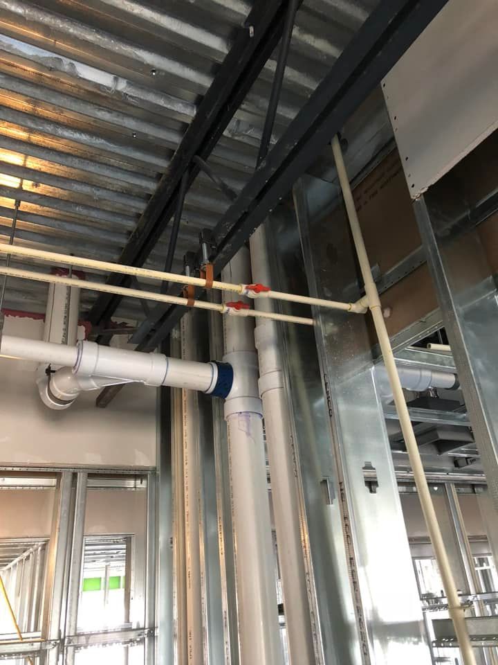 A bunch of pipes are hanging from the ceiling of a building under construction.