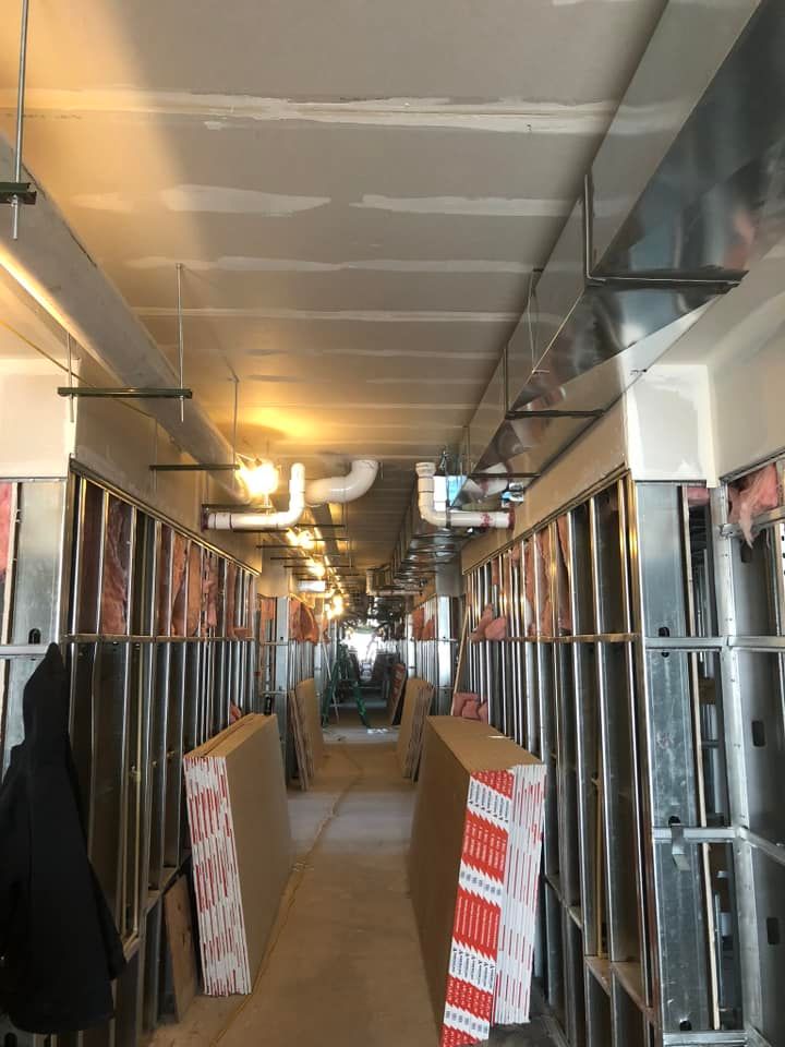 A long hallway with a lot of pipes hanging from the ceiling.
